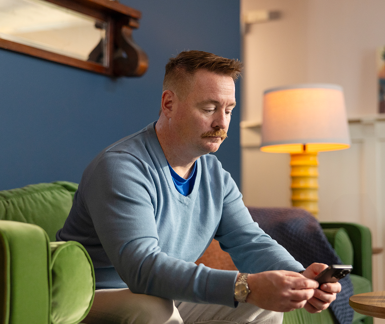 Andrew, a real indolent systemic mastocytosis patient who takes AYVAKIT® (avapritinib) checking his phone