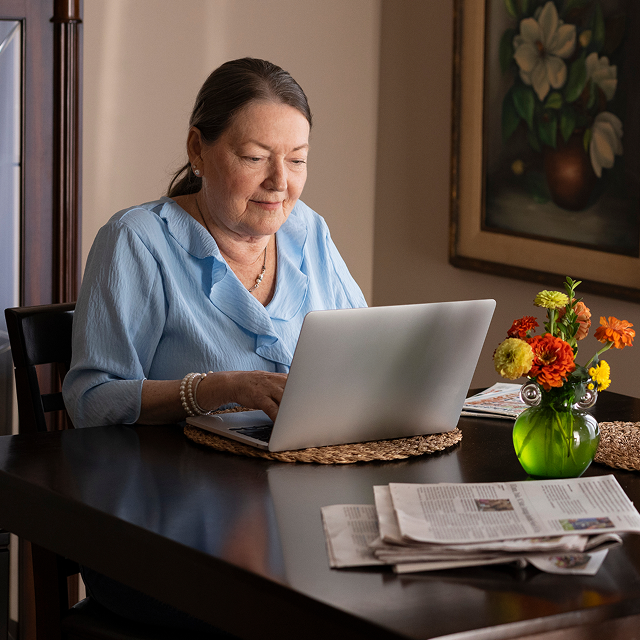 Gloria, a real indolent systemic mastocytosis patient who takes AYVAKIT® (avapritinib), working on her laptop at a table